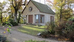 Une maison en pierre avec un toit à deux versants, de grandes fenêtres et une porte.