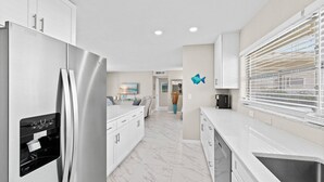 Una cocina moderna con un refrigerador de acero inoxidable, armarios blancos y piso de mármol.