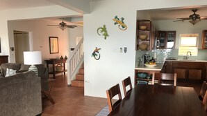 Un salón espacioso con comedor, cocina y una escalera que conduce a otro nivel.