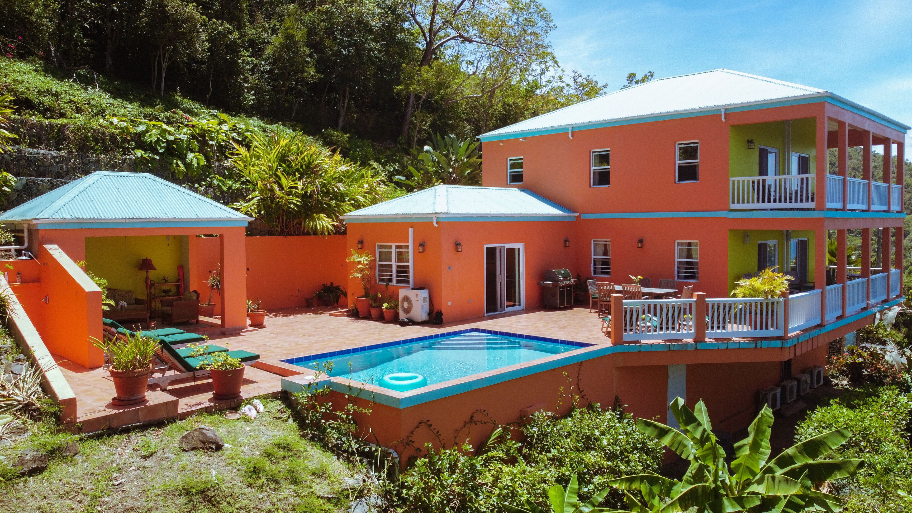 Um edifício de dois andares com piscina, área de estar ao ar livre e um alpendre coberto.