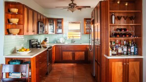 Una cocina con armarios de madera, un refrigerador, un lavamanos y una estantería para vinos.