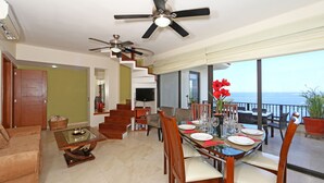 A dining area with a table set for four, a sofa, and a TV in the background.