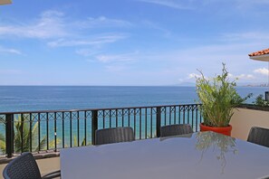 A balcony with a view of the sea, a table, chairs, and a potted plant. - 🍹PUERTA AL MAR🍹 PENTHOUSE/BEACHFRONT–5 BALCONIES/POOL/STEPS 2 TOWN–WONT LAST! (Puerto Vallarta)