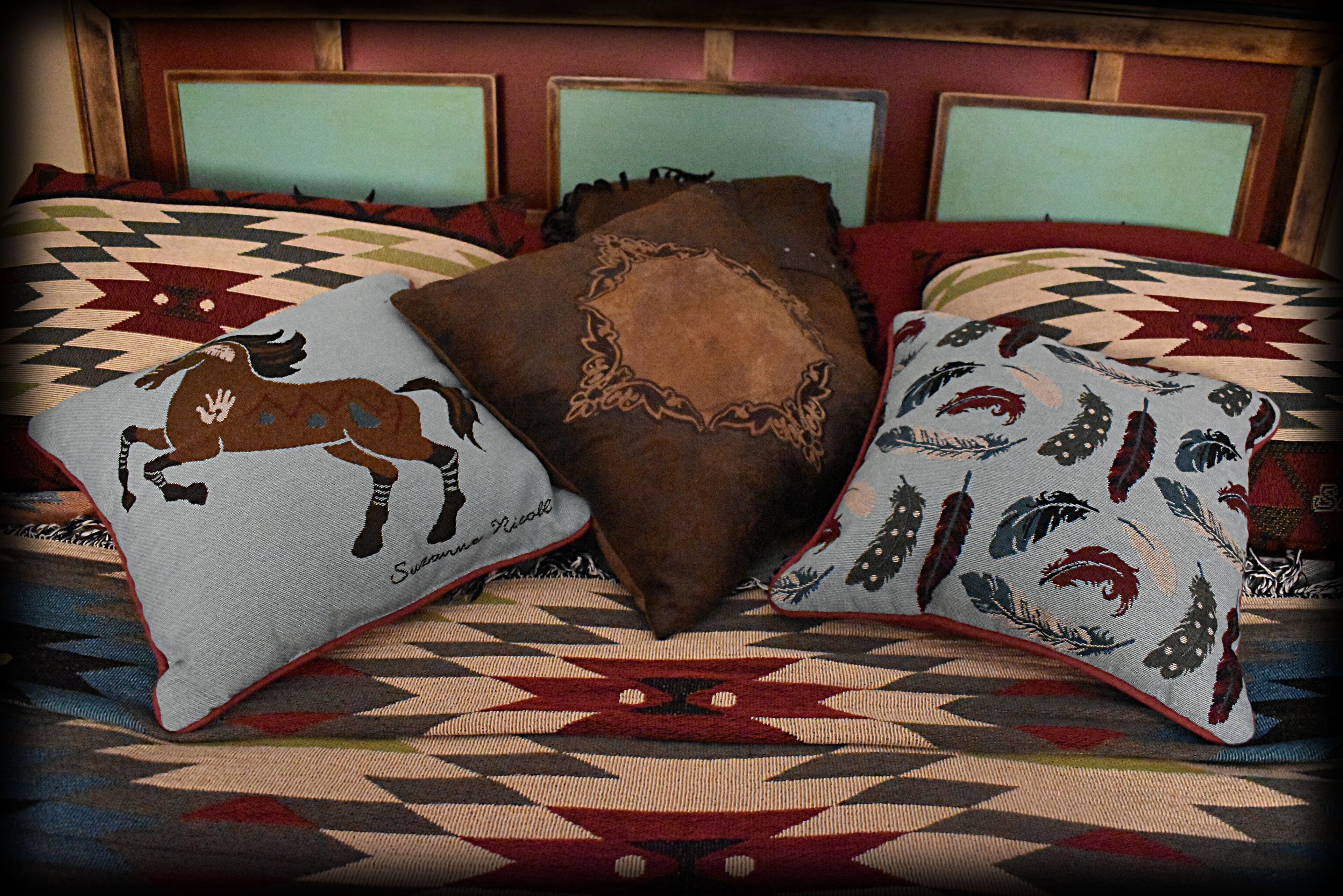 Een bed met drie decoratieve kussens, een beddekleed met dessin en een houten hoofdbord.