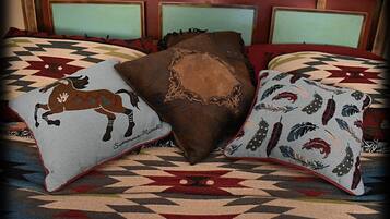 Een bed met drie decoratieve kussens, een beddekleed met dessin en een houten hoofdbord.
