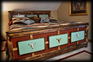 Un lit avec une tête de lit en bois, plusieurs oreillers et une courtepointe.