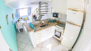 Een keuken met een spiraaltrap, een magnetron, een koelkast en een gootsteen.