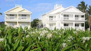 A two-story white building with balconies, surrounded by greenery. - Bayfront 1BR Apt - Central Location & GREAT Rates! (Governor`s Harbour)