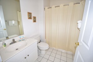 A bathroom with a sink, toilet, and shower curtain.
