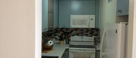 A compact kitchen with a microwave, stove, and refrigerator.