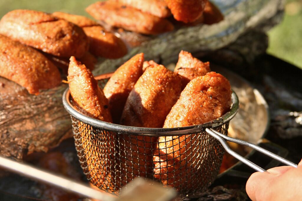A basket of fried food items being held over a grill.