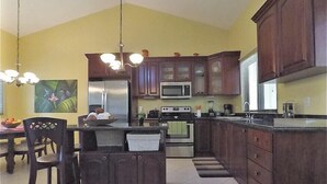 Cucina con pensili in legno scuro, frigorifero in acciaio inossidabile, microonde e piano cottura.