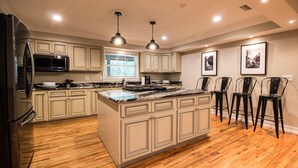 A spacious kitchen with a large island, wooden flooring, and pendant lighting. - Secluded Waterfront Retreat With Private Dock                                    (Ocklawaha)
