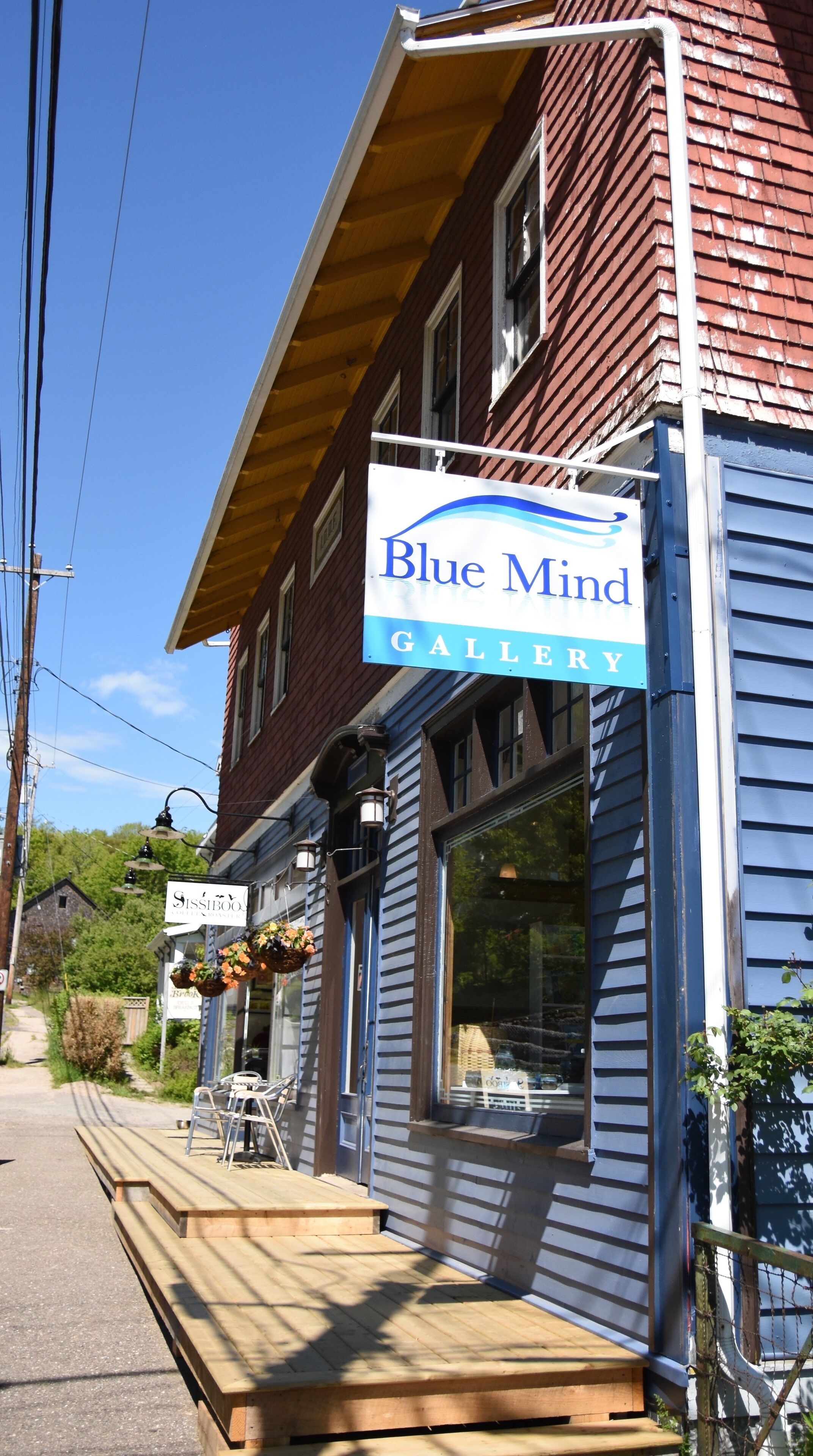 Un bâtiment portant une enseigne « Blue Mind Gallery » et dont la devanture, avec une vitrine, est bien visible.