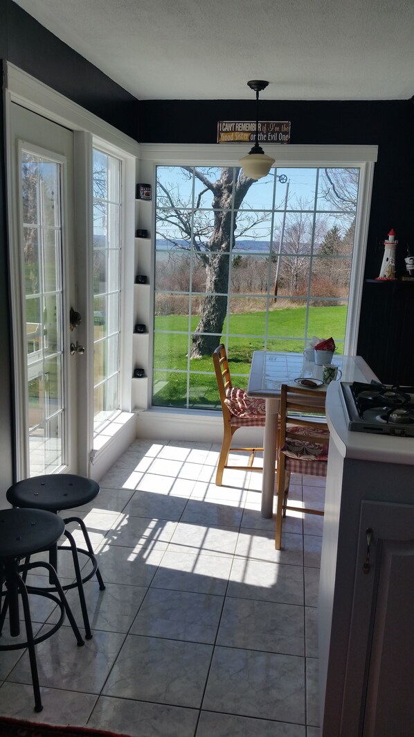 A kitchen with a large window, a dining table, and a chair. - Casa Moana, Lovely old house overlooking St. Mary`s Bay, with free breakfast. (Plympton)