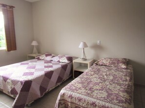 A room with two beds, each with a patterned bedspread and a nightstand with a lamp. - 3 SEA-FRONTED Houses - Beach of Mariscal, Bombinhas, SC - HOUSE #7 (Bombinhas)