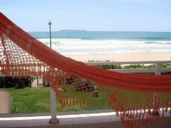 A hammock with a view of the ocean and a grassy area. - 3 SEA-FRONTED Houses - Beach of Mariscal, Bombinhas, SC - HOUSE #7 (Bombinhas)