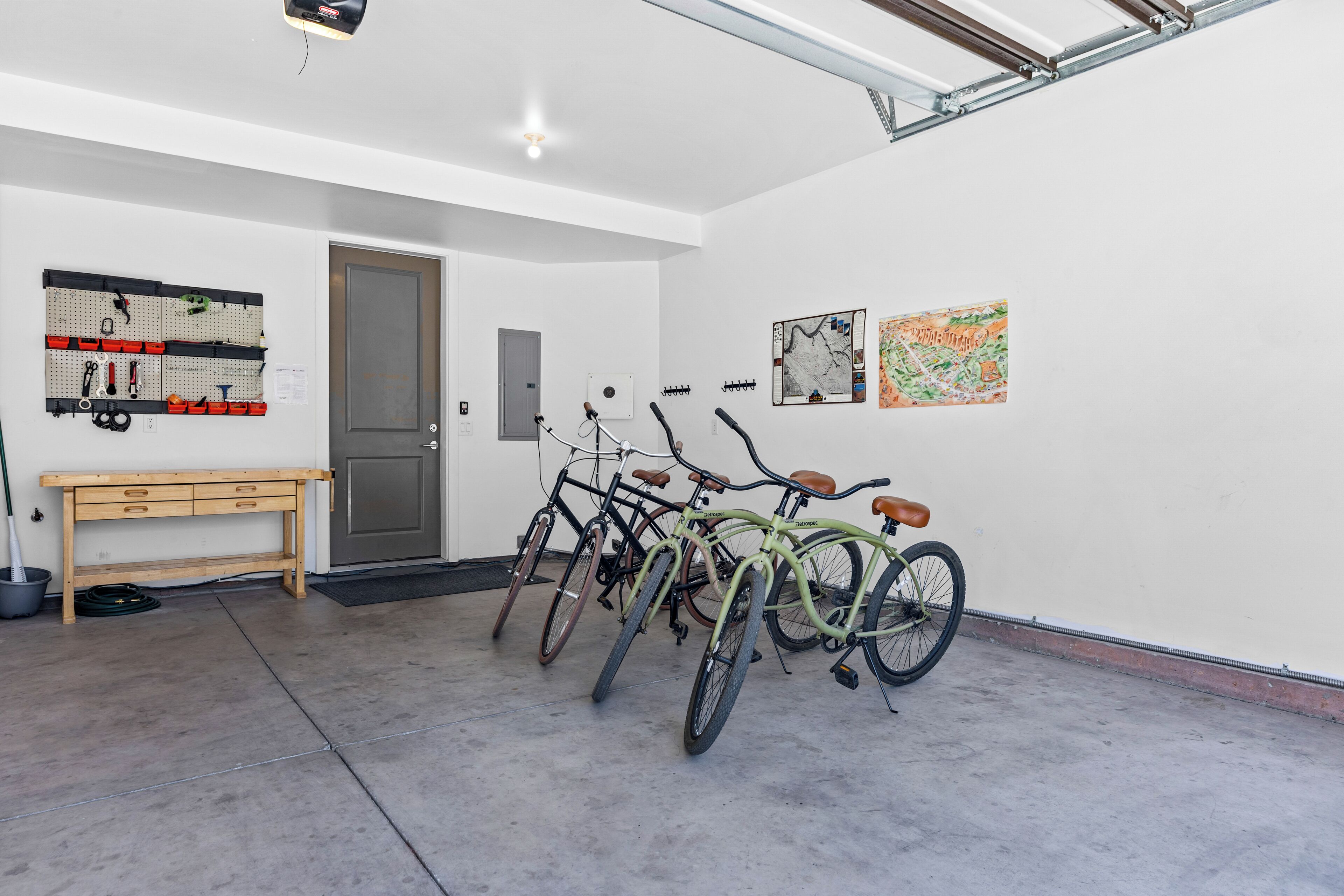 A clean, well-organized room with bicycles, a pegboard with tools, and a map on the wall.