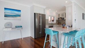 Une cuisine moderne dotée d’un grand îlot central, d’appareils électroménagers en acier inoxydable et de tabourets de bar bleu clair.