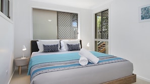 Relax in a spacious room with a large bed, bedside table, and window overlooking a staircase leading to an outdoor area.