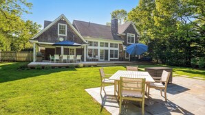 A two-story house with a covered patio area and a lawn. - Wainscott Southampton Estate Timeless luxury with a private pool,... (Wainscott)