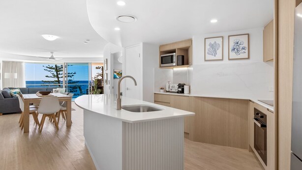 Una cocina moderna con una isla central, armarios de madera y vista al océano.