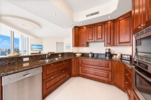 A modern kitchen with granite countertops, stainless steel appliances, and wooden cabinetry.