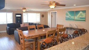 A dining area with a wooden table and chairs, a ceiling fan, and a kitchen island with a granite countertop. - Major's Toy Box - Amazing Home Havasu Landing  (Havasu Lake)