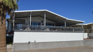A modern building with a flat roof, a covered balcony, and a brick base. - Major's Toy Box - Amazing Home Havasu Landing  (Havasu Lake)