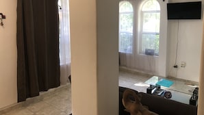 Ein Wohnzimmer mit einer Couch, einem Glastisch und einem an der Wand befestigten Fernseher.