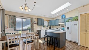Una cocina moderna con piso de madera, una isla central y un comedor con sillas.