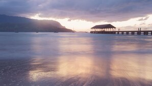A pier extending into calm waters with a covered structure at the end. - Princeville Condo with AC, Pool, Garage, Beach Gear 27B (Princeville)