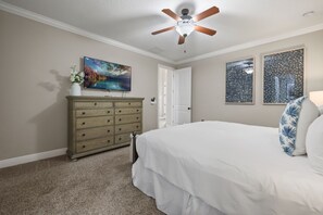 Ein Schlafzimmer mit einem Bett, einer Kommode, einem Deckenventilator und Kunstwerken an den Wänden.