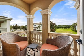 Ein Balkon mit Korbmöbeln und Blick auf einen Golfplatz.