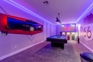 Ein Zimmer mit Billardtisch, Neonreklamen und einer Neoninstallation an der Wand.