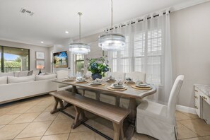 Comedor con mesa de madera dispuesta para seis personas, rodeado de sillas blancas.