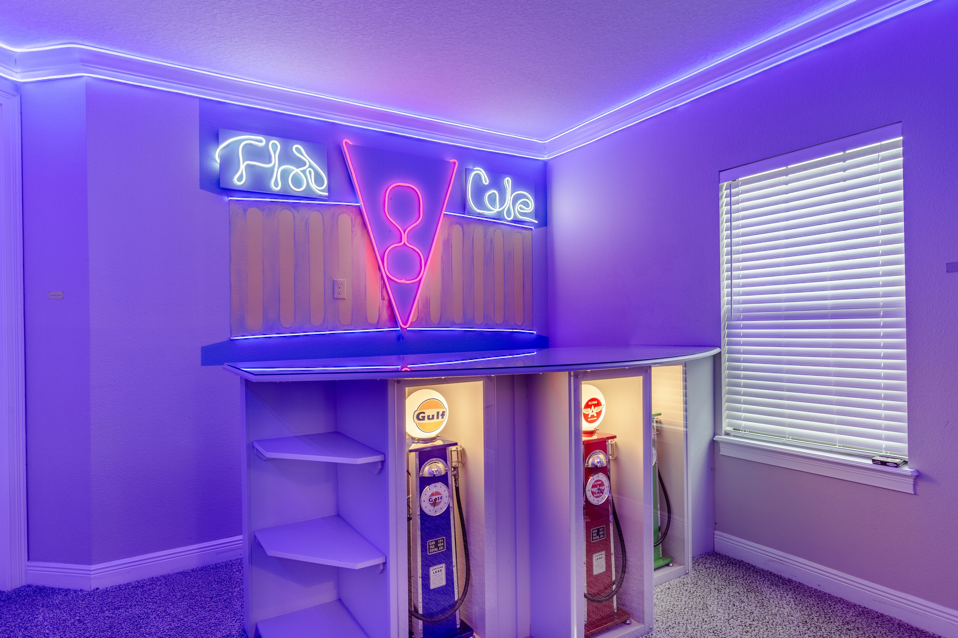 A room with a sloped ceiling, neon signs reading "Flu" and "Coke," and two gas pumps labeled "Gulf."