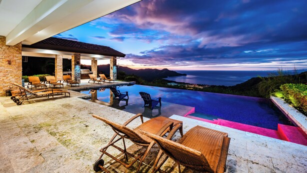 Zona de piscina con mobiliario exterior y vista al mar.