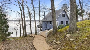Una casa con un muelle que se adentra en un lago, rodeada de árboles.