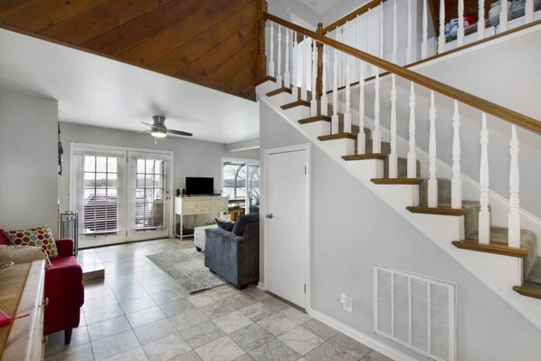 A spacious living room with a staircase, a television, and a dining area.