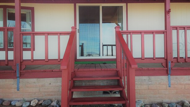 A staircase leading to a porch with a view of a building across the street.