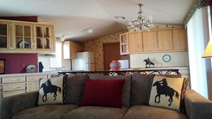 A cozy living room with a sofa featuring horse-themed cushions, wooden cabinets, and a chandelier.