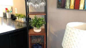 Una cocina con cubierta negra, un lavamanos blanco, una estantería para vinos y una planta en maceta.