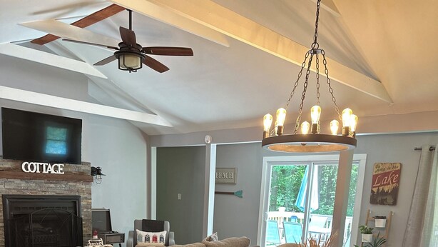 A spacious living room with a fireplace, a dining area with a wooden table and chairs, and a ceiling fan. - Pier Joy: Two private cottages on 2.5 wooded acres, close to Union Pier beaches (Union Pier)