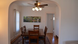 A dining room with a wooden table and chairs, a ceiling fan, and a painting on the wall. - HomeAway Residential Apartment (Dearborn)