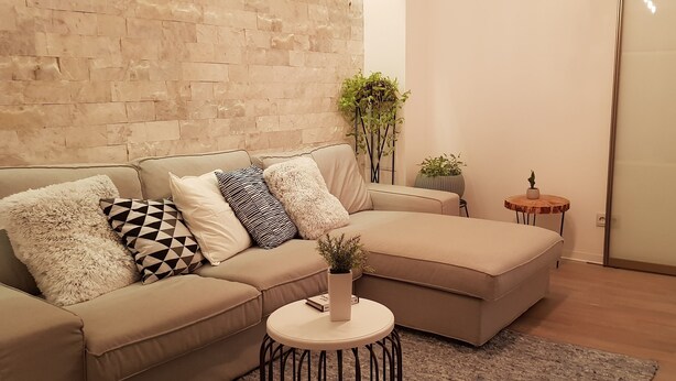 A living room with a beige sofa, a round coffee table, and a potted plant.