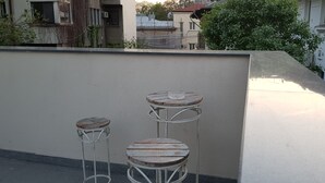 Three metal bar stools with wooden seats against a plain wall.