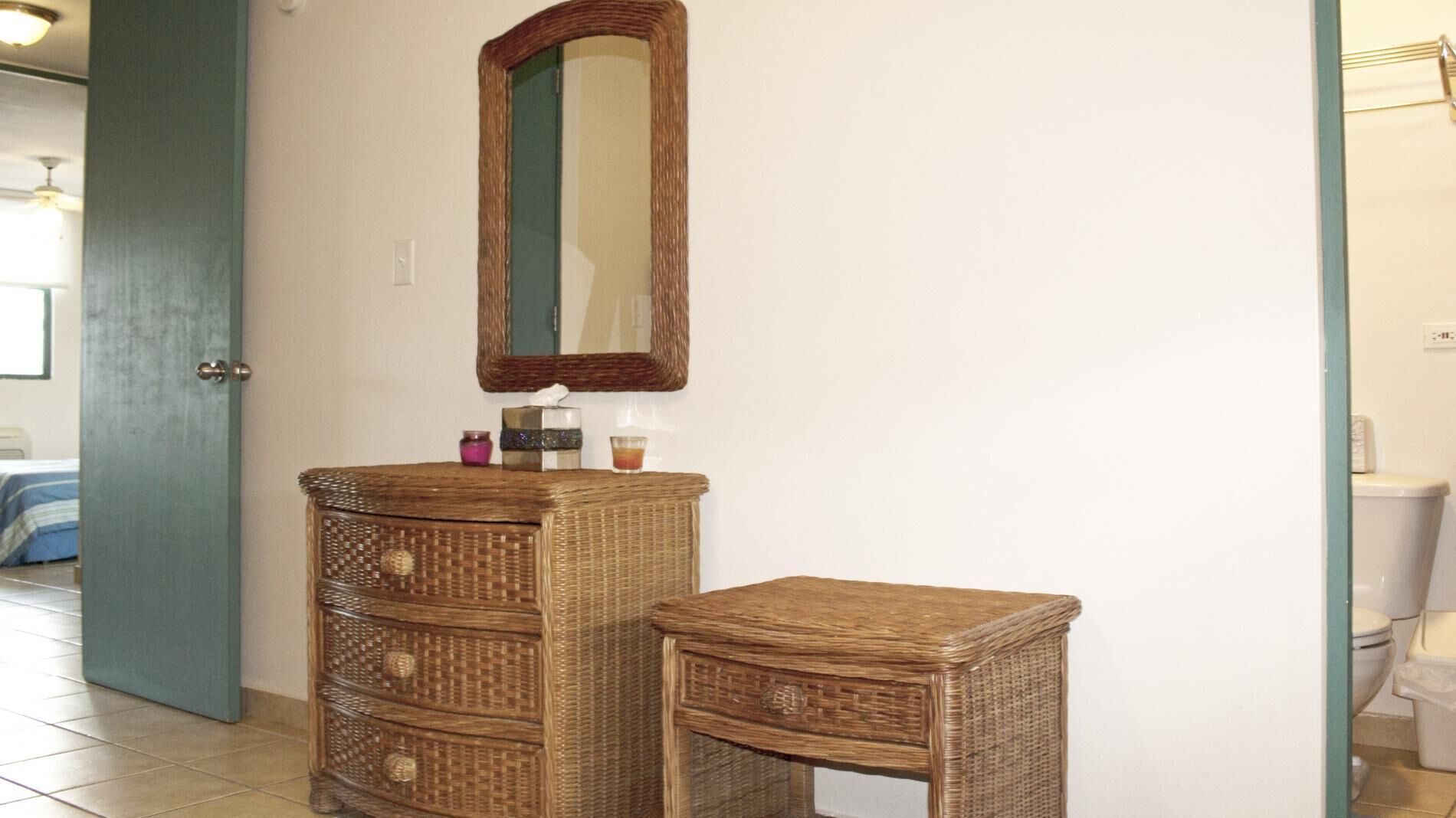 Une salle de bain avec un meuble-lavabo en osier, un miroir et des toilettes.