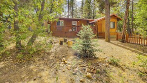 A cabin with a deck, surrounded by trees and a forested area. - 4 Mi to Rainbow Lake! Cozy Forest-View Gem w/ Deck (Lakeside)