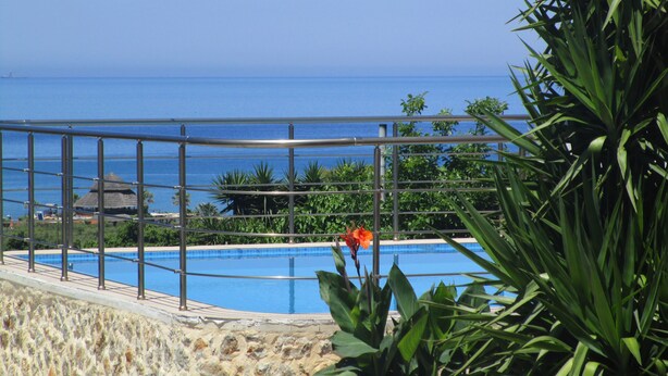 A pool with a view of the ocean, surrounded by greenery and a metal railing. - Villa Balos with fantastic sea view (Chania)